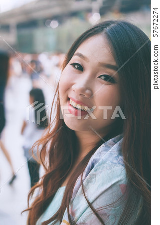 Beautiful Asian woman smiling with outdoor scene. 57672274