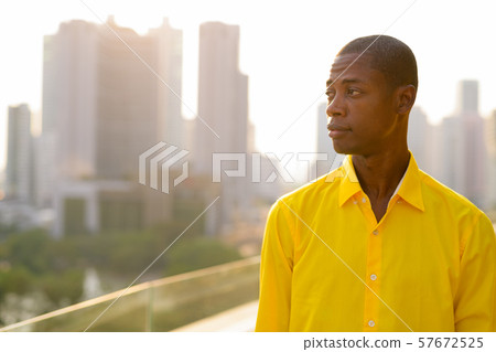 Young bald African businessman thinking against view of the city 57672525