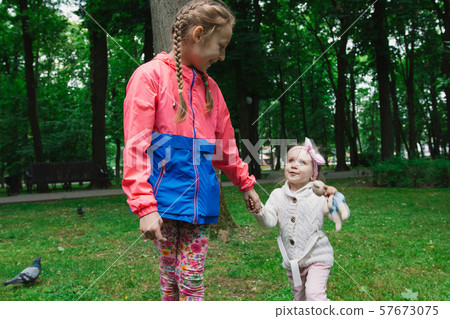 Children walk in the park on a day off. The sun is Children walk in the park on a day off. The sun is 57673075