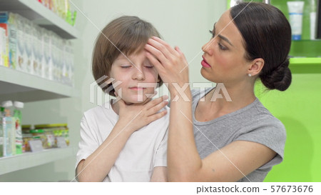 Beautiful woman looking disturbed as her little son coughing and having fever 57673676