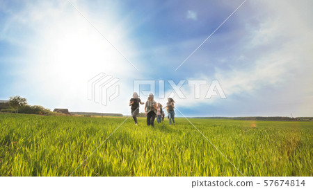 Happy friends run against the backdrop of a beautiful sky and sun. 57674814