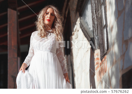 Fashion photo of beautiful woman in wedding dress posing outdoor. 57676262