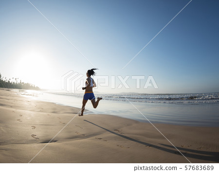 young fitness woman running at sunrise beach 57683689