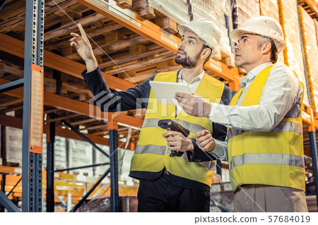 Kind bearded male person pointing at shelf with wares 57684019