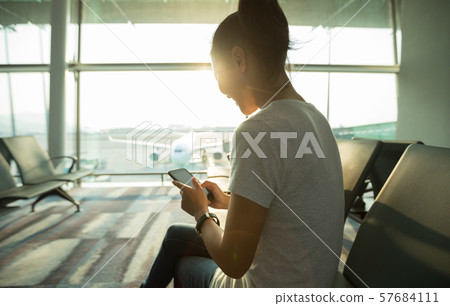 Woman passenger using mobile phone in airport Woman passenger using mobile phone in airport 57684111