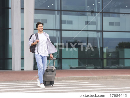 Happy millennial guy going out of airport building 57684443