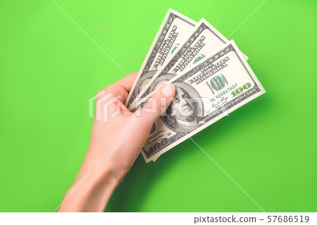 Dollars in woman hand on green background. 57686519