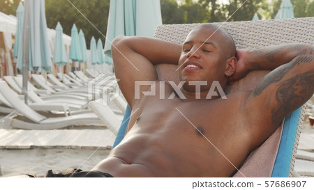 Handsome African man sunbathing at the beach Handsome African man sunbathing at the beach 57686907