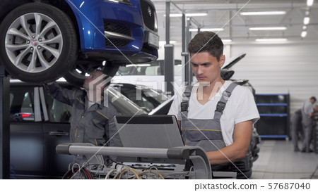 Young car mechanic using laptop at the garage 57687040