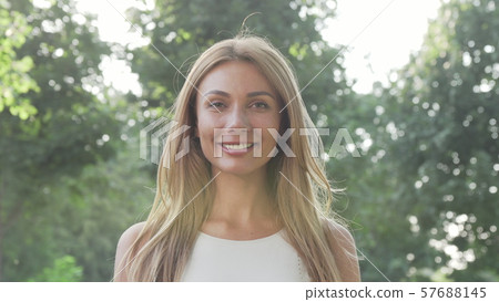 Beautiful happy woman enjoying relaxing outdoors in the park in summer evening 57688145
