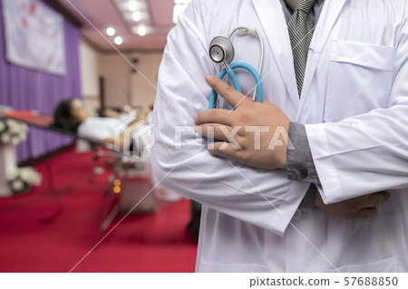 Doctor in gown uniform with stethoscope standing in blood donor room. Doctor in gown uniform with stethoscope standing in blood donor room. 57688850