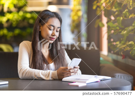 Brunette intelligent girl studying in cafe, holding smartphone 57690477