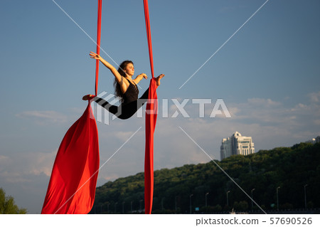 Beautiful and flexible female circus artist dancing with aerial silk with sky and river coastline on 57690526