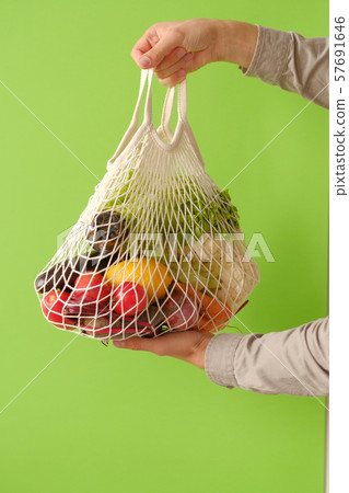 hand holding string shopping bag with vegetables 57691646