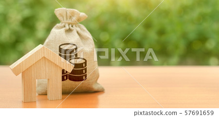 Wooden house figurine and a money bag. Family budget, control and reduction of expenses. subsidized funds. Mortgage loan for purchase housing, construction or modernization. Tax, building maintenance. 57691659