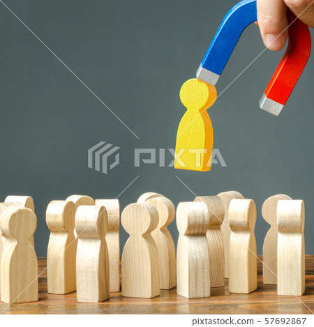 A hand with a magnet pulls yellow golden human figure out of the big crowd of people. Search for talented workers Labor migration, the demand for good specialists. Recruiting new workers, headhunters. A hand with a magnet pulls yellow golden human figure out of the big crowd of people. Search for talented workers Labor migration, the demand for good specialists. Recruiting new workers, headhunters. 57692867