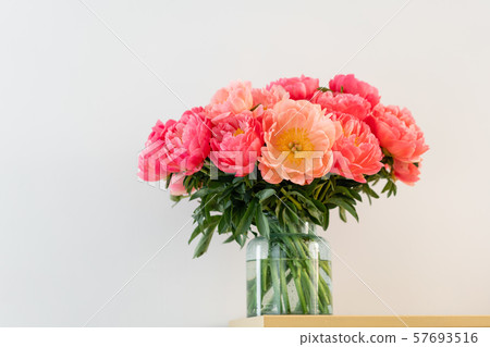 Coral peonies in a glass vase on wooden table.. Beautiful peony flower for catalog or online store Coral peonies in a glass vase on wooden table.. Beautiful peony flower for catalog or online store 57693516