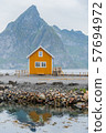 A yellow fishing cabin in Sakrisoy, a small fishing village in Moskenes Municipality on Lofoten islands in Nordland county, Norway with a mountain in background 57694972
