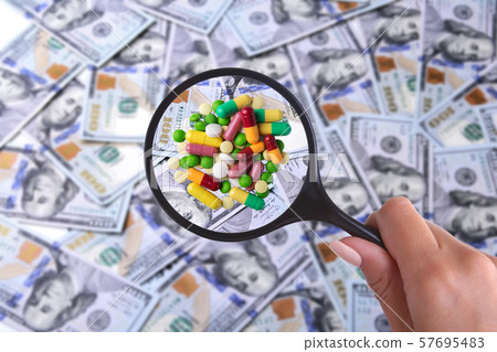 concept of Health insurance. Assortment pills in magnifier against the background of Many dollar concept of Health insurance. Assortment pills in magnifier against the background of Many dollar 57695483