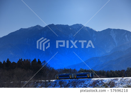 A hybrid train that travels along the snowy Koumi Line against the background of Minami Alps, Mt. 57696218