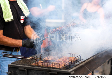 The cook fries juicy steaming meat on a charcoal 57696895
