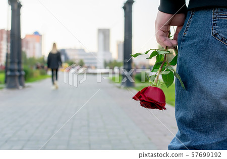 red rose flower in the hand of the guy on the background of the girl red rose flower in the hand of the guy on the background of the girl 57699192