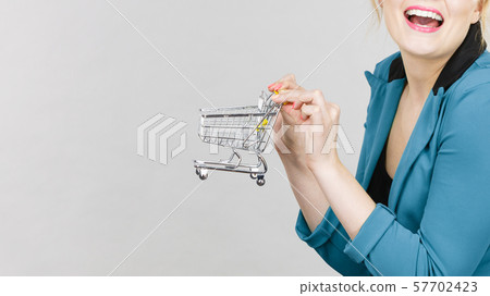 Happy woman holding small tiny shopping cart Happy woman holding small tiny shopping cart 57702423
