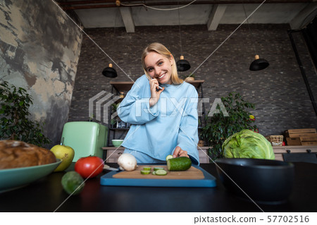 Beautiful girl talking on the mobile phone in kitchen at home 57702516