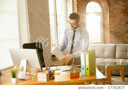 A young businessman moving in office, getting new work place A young businessman moving in office, getting new work place 57702677