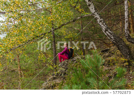 young woman hiker sits resting on a cliff among a young woman hiker sits resting on a cliff among a 57702873