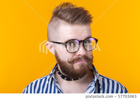 Young positive trendy man hipster with a mustache beard and fetish necklace in shirt posing on a Young positive trendy man hipster with a mustache beard and fetish necklace in shirt posing on a 57703063