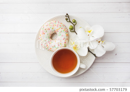 Cup of tea and donuts, white orchid on white table with copy space. Flat lay, top view. 57703179