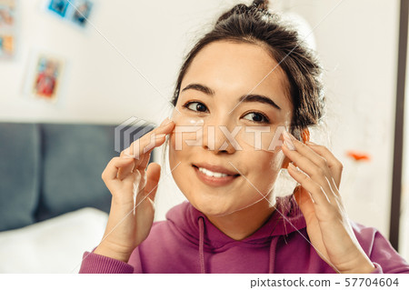 Young woman moistening her skin in the morning Young woman moistening her skin in the morning 57704604