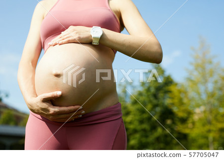 Pregnant woman walking outdoors 57705047