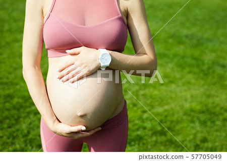 Pregnant woman standing outdoors 57705049