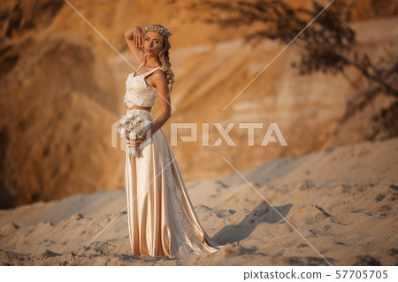 Beautiful bride is wearing fashion flying dress and wreath in the great desert in Dubai. 57705705