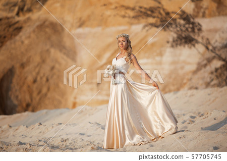 Beautiful bride is wearing fashion flying dress and wreath in the great desert in Dubai. 57705745