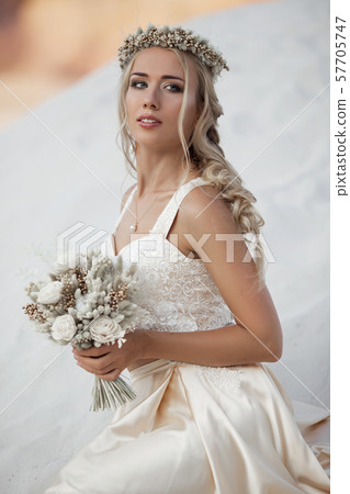 Portrait of beautiful bride is wearing fashion flying dress and wreath in the great desert in Dubai. 57705747