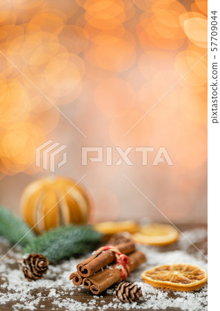 Cinnamon and christmas decoration on wooden table. Spruce branch, orange and snow. Morning in the Cinnamon and christmas decoration on wooden table. Spruce branch, orange and snow. Morning in the 57709044
