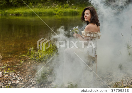 One bride is sitting on the banks of a foggy One bride is sitting on the banks of a foggy 57709218