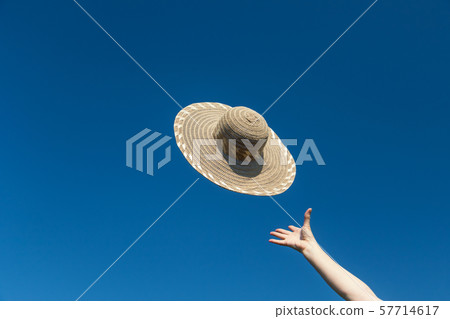 Female hand is throwing a straw hat 57714617