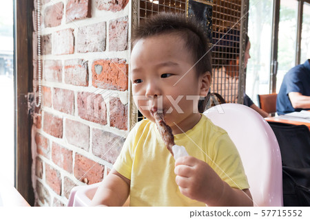 拿著羊羔肋骨的逗人喜愛的男嬰表示手中 57715552
