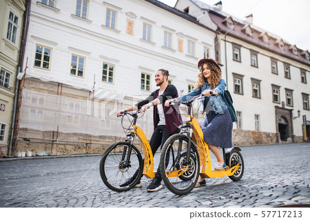 Young tourist couple travellers with electric scooters in small town. 57717213