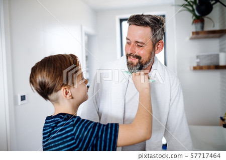Mature father with small son in the bathroom in the morning, combing. Mature father with small son in the bathroom in the morning, combing. 57717464