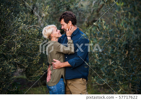 Young affectionate couple standing outdoors in olive orchard, hugging. 57717622