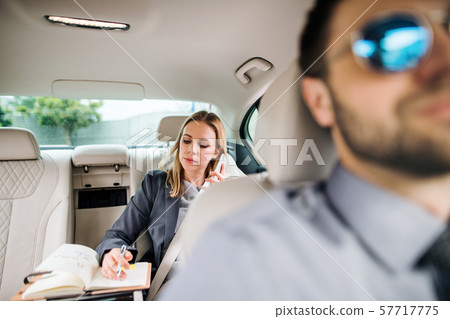 Business woman with smartphone sitting on back seat in taxi car, talking. Business woman with smartphone sitting on back seat in taxi car, talking. 57717775