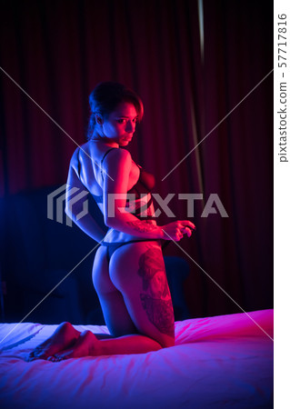 Young confident woman with tattoos in a sexy underwear sitting on the bed on her knees and posing 57717816