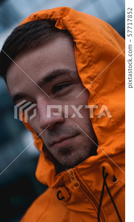 Young man in orange work uniform - glass building on background 57717852