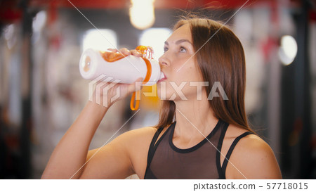 An athlete woman drinking water in the gym An athlete woman drinking water in the gym 57718015