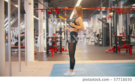 A sportive woman in sports clothes training in the gym - holding the handles and prepares to lean 57718030